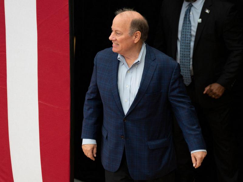 Former Detroit Mayor Mike Duggan walks near a large American flag