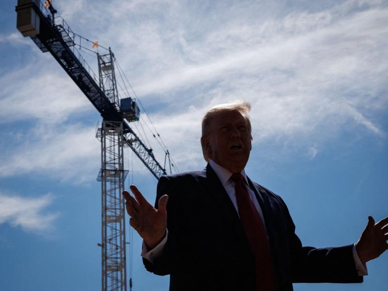 President Donald Trump stands in front a crane where the new East Wing of the White House is being constructed